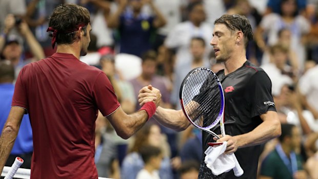 John Millman of Australia greets Roger Federer of Switzerland at the net.
