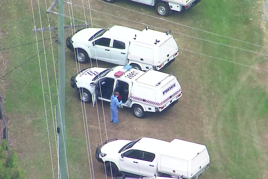 Aerial photo of three police cars with an officer in blue oversuit next to one