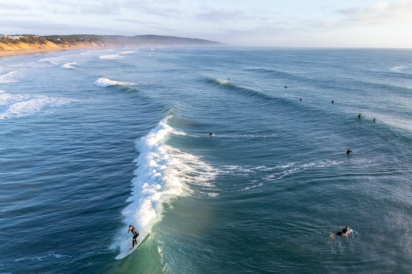 An aerial view of a beach with a surfer riding a wave