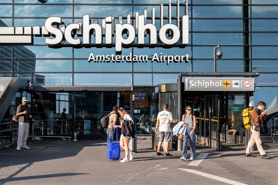 Travellers in front of the entrance to the central hall of Schiphol airport Amsterdam.