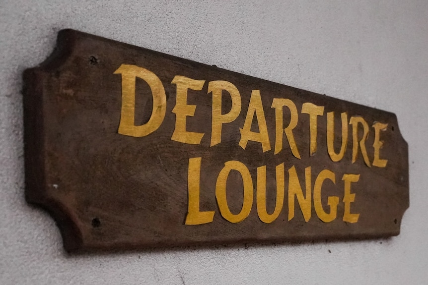 A wooden sign which reads 'departure lounge'