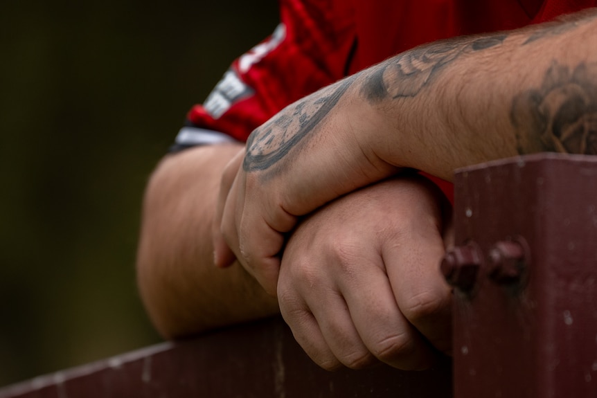 A close-up shot of a man's hands with some tattoos visible on his hands and arm.