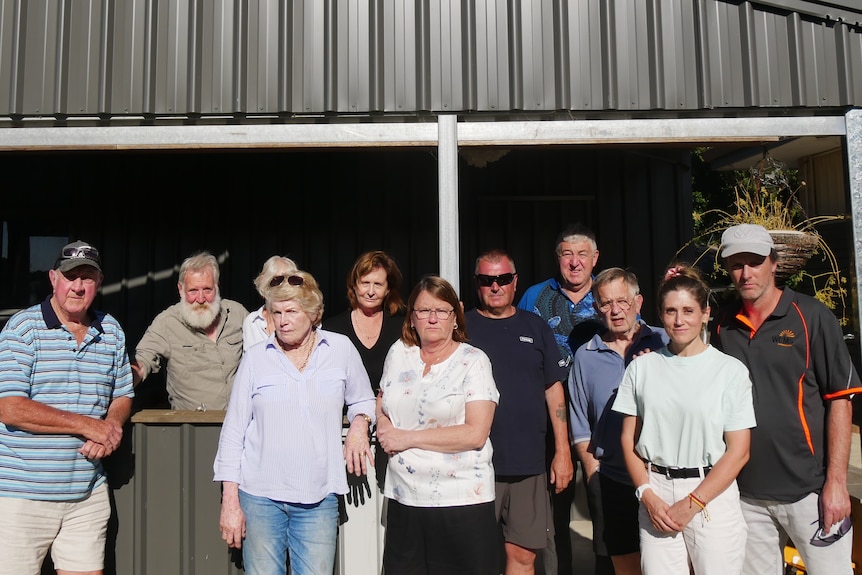 A group of people standing together in front of shed