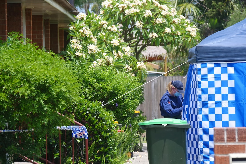 police officer with mask walks into police tent set up in front of unit