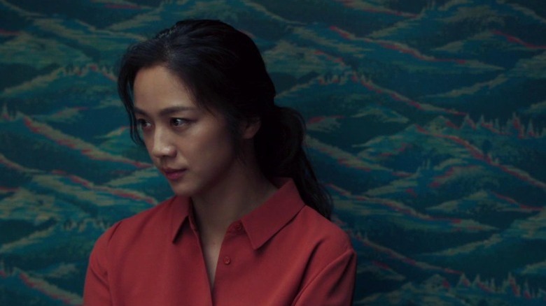 Tang Wei as Seo-rae standing in front of a blue wall in Decision to Leave