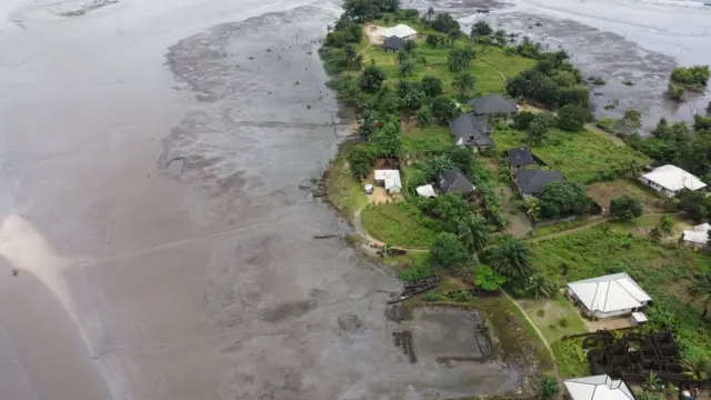 Aerial view of a community in Ogoni land. Shows vegetation, houses and river.