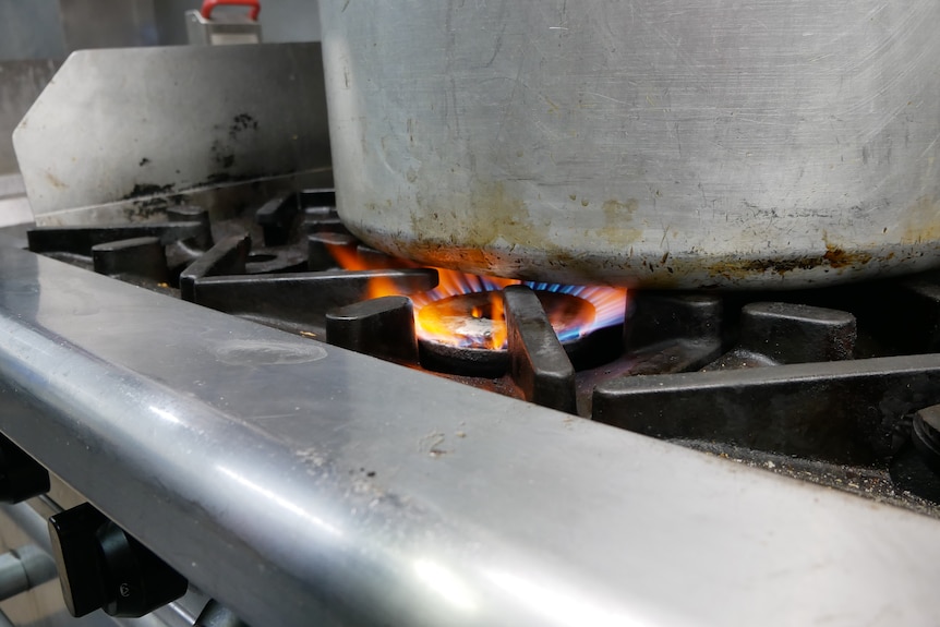 A metal pot sitting on a gas ring in a commercial kitchen.