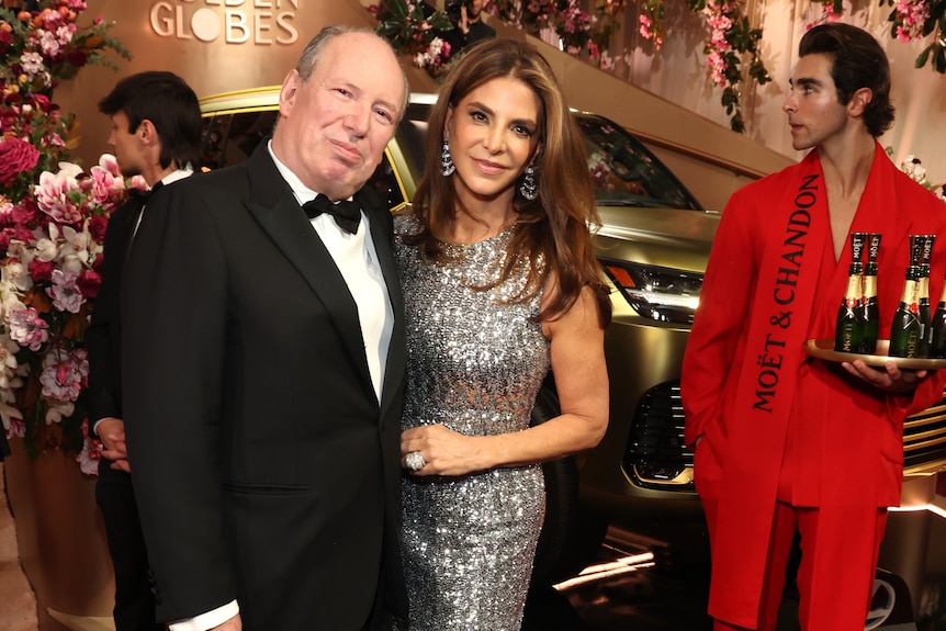 A man in a tuxedo with a woman in a silver gown. 