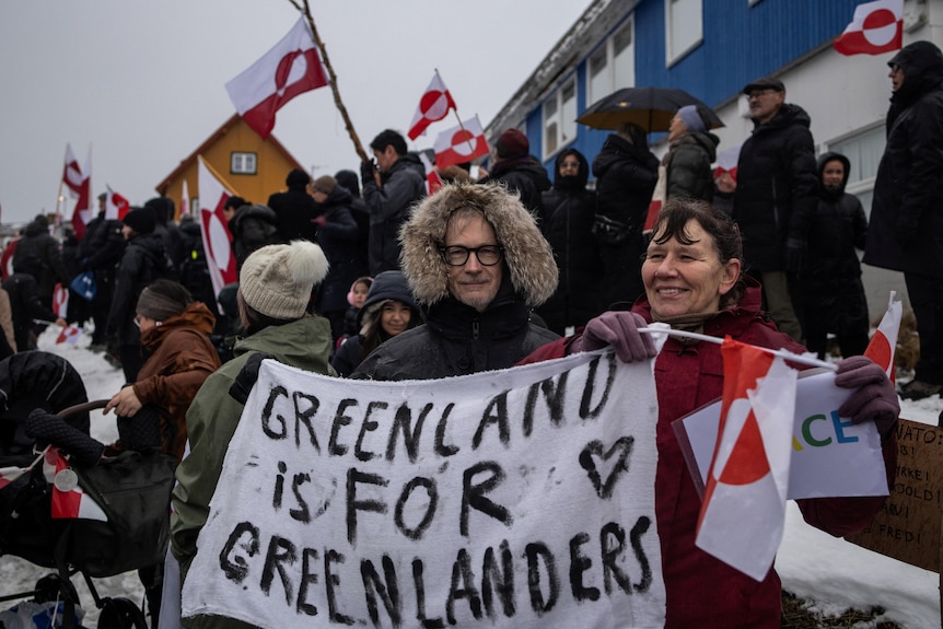 A man holding a sign that reads 'Greenland is for Greenlanders'