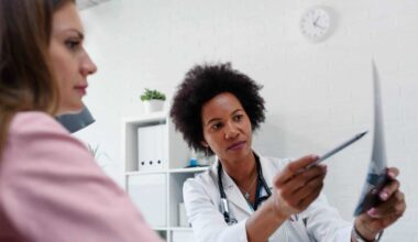 A doctor sits with a patient and uses a pen to point to certain parts of her mammogram scan
