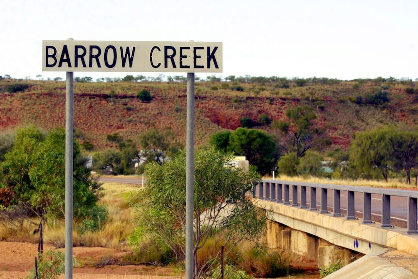 An outback landscape with a sign that reads Barrow Creek.