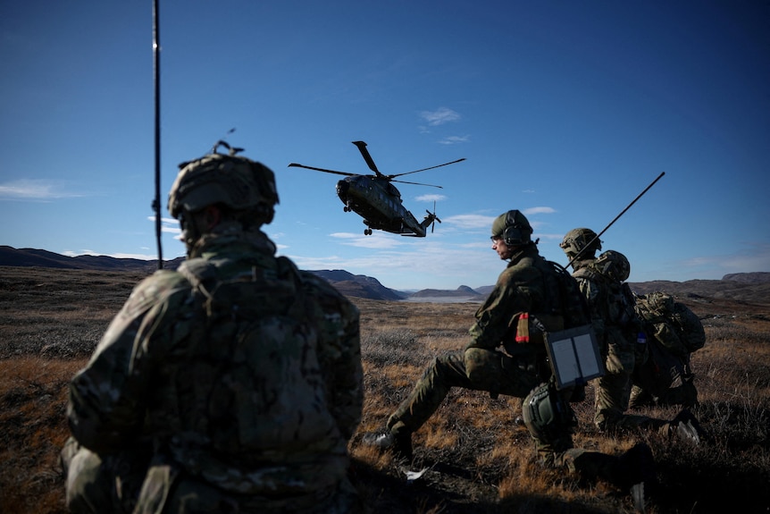 A Danish helicopter flies near soldiers