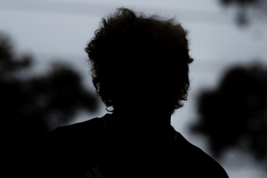 The silhouette of a man against a darkened background.