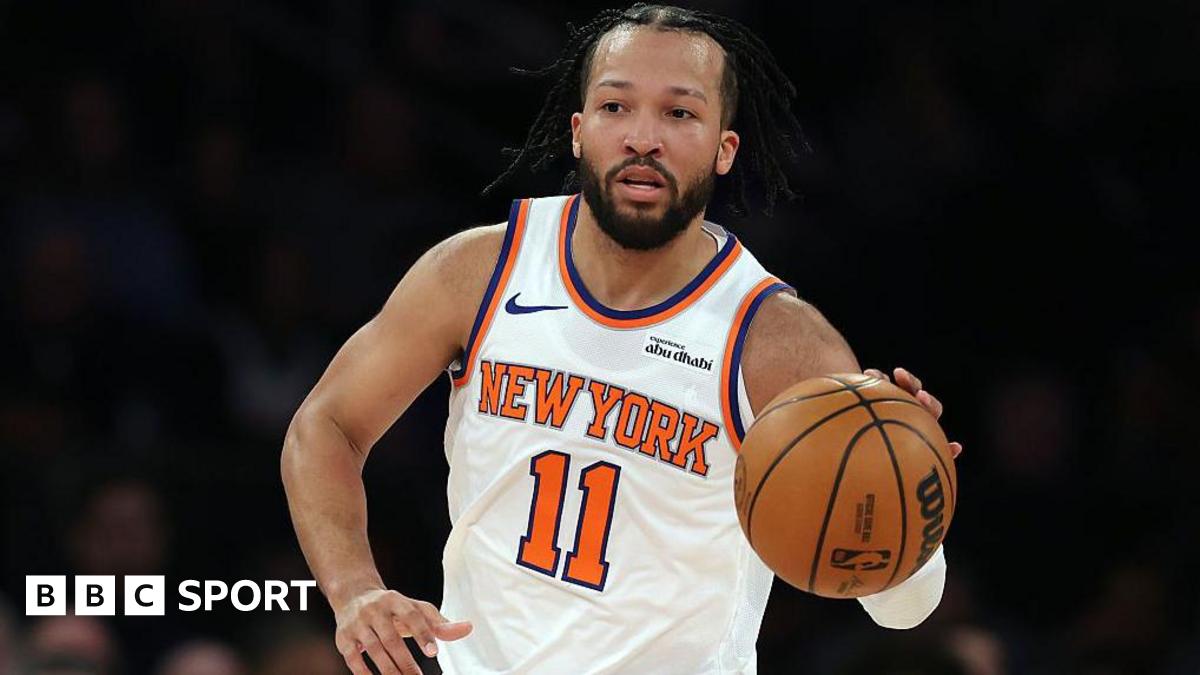Giannis Antetokounmpo is wearing a green Milwaukee Bucks vest and holding a basketball