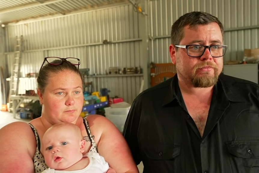 Arie Eddy with his partner and three-monthold baby. They have neutral expressions.