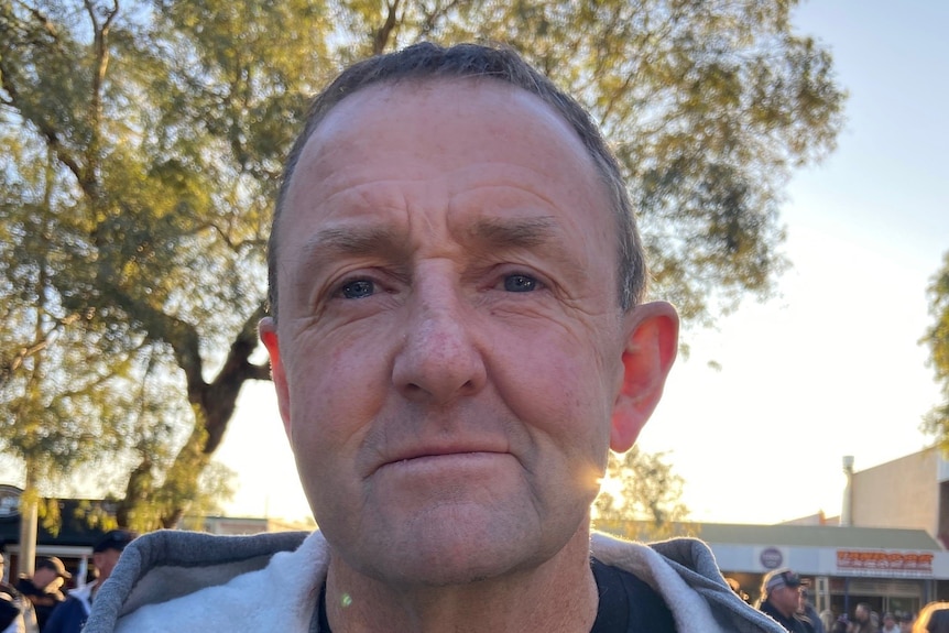 A man wearing a black t-shirt, grey hoodie with sunglasses