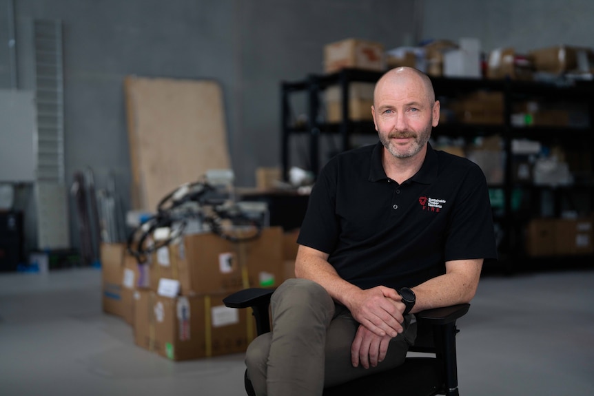 Man sits on chair, smiling for photo