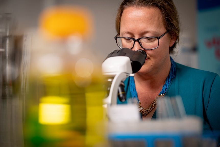 Faith Coleman looking down at a microscope.