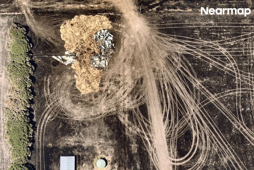 an aerial image of a farming property with three structures, one completely flattened in burned surrounding