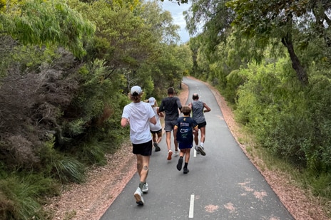 A wide shot of five people running
