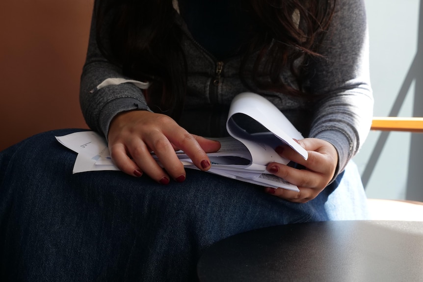 A close up of a woman's hand shuffling though papers. 