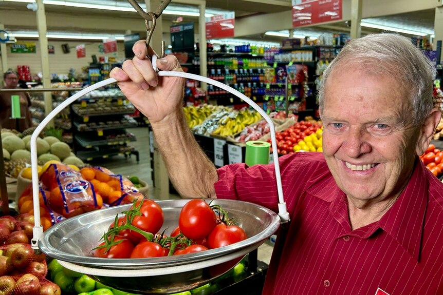 man in supermarket with red tomatoes in weighing scales