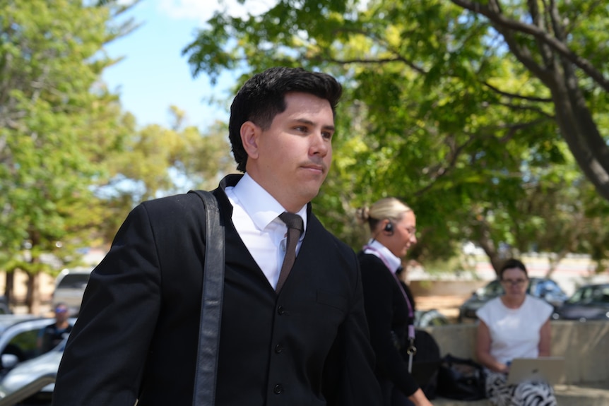 Defence lawyer Reid Hogan dressed for court walks along a street. 