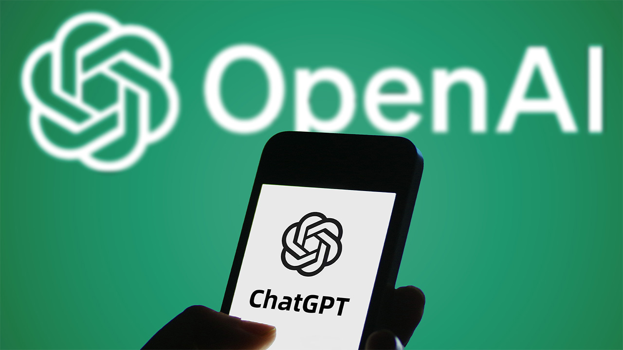 Smartphone displaying ChatGPT logo held in front of white OpenAI logo on green background