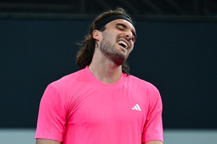 Tennis player Stefanos Tsitsipas throws his head back during a match.