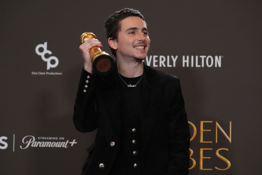 A man holds a golden award.