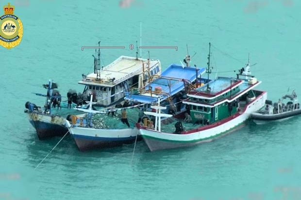 Three larger blue wooden boats and a small boat anchored in water.