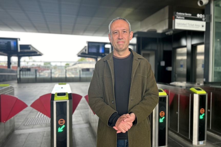 Man standing in front of ticket gates at a train station.