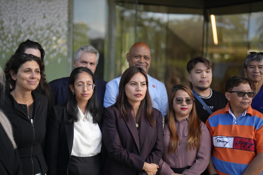 A group of men and women stand outside a court.