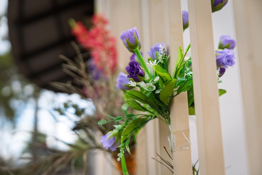 A close-up of purple flowers that have been left in tribute outside a police station.