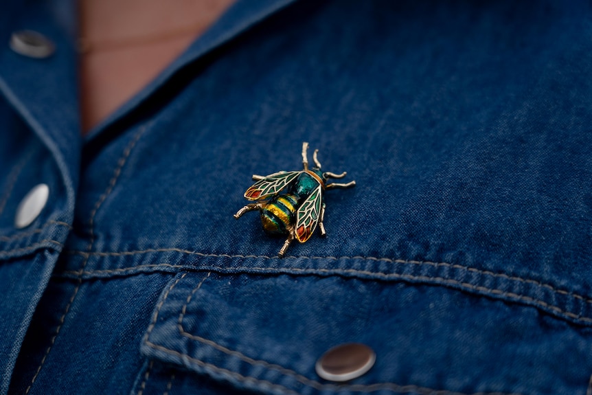 Woman wearing a bee broach clipped to blue denim dress