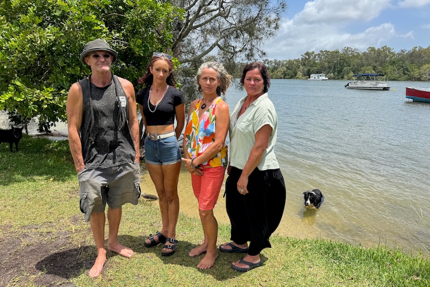 Four people on edge of water with houseboats in background.