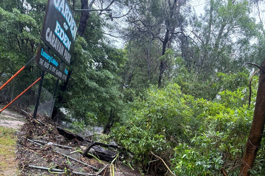 Flood debris rests near a caravan park sign.
