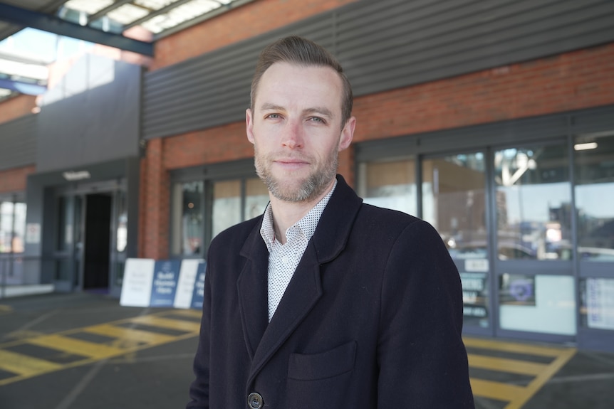 man smiles neutrally at camera