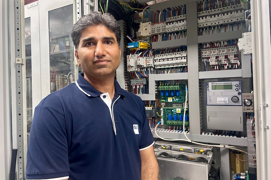 man with a blue shirt in front of electrical equipment