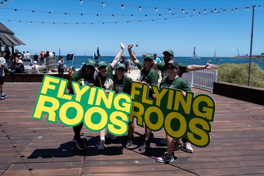 People posing for a picture holding banners saying 'Flying Roos'