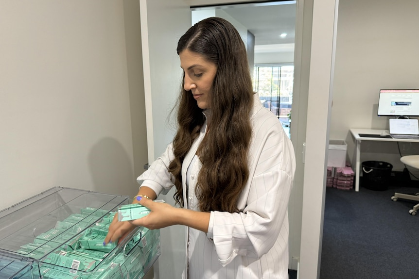 Slightly smiling Diana Gligorov has long dark hair, is packing reusable straws.