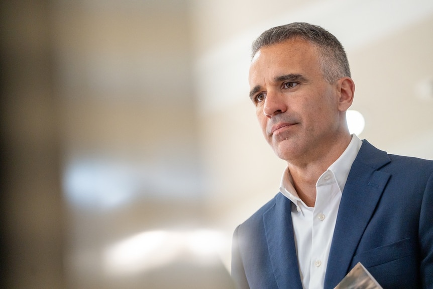 A man in a blue suit jacket at a media conference.