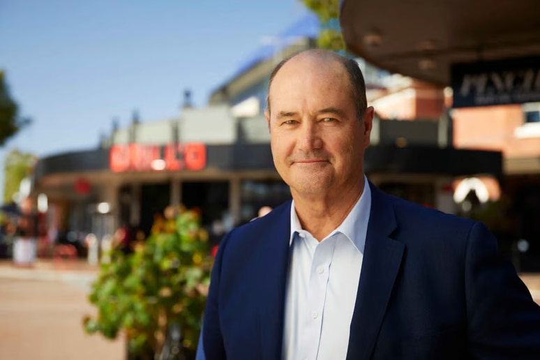 A man in suit smiling while in a street.