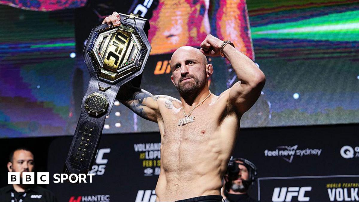 Alexander Volkanovski raises his featherweight title at the UFC 325 news conference