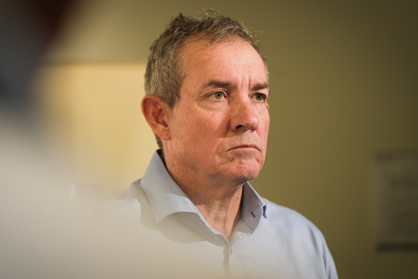 A politician in a button-up shirt, looking off to the side of the camera.