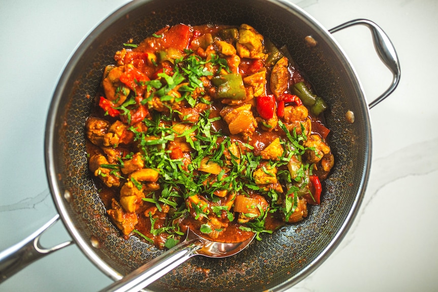 A large pan filled with chicken jalfrezi, a tomato-based chicken curry that is stir fried with capsicums. A weeknight meal.
