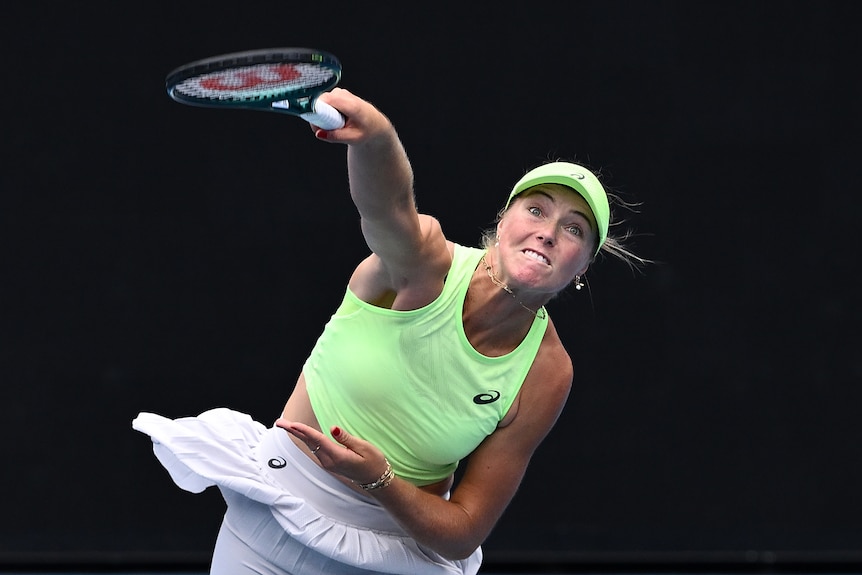 Olivia Gadecki serves the ball in a tennis match, wearing green singlet