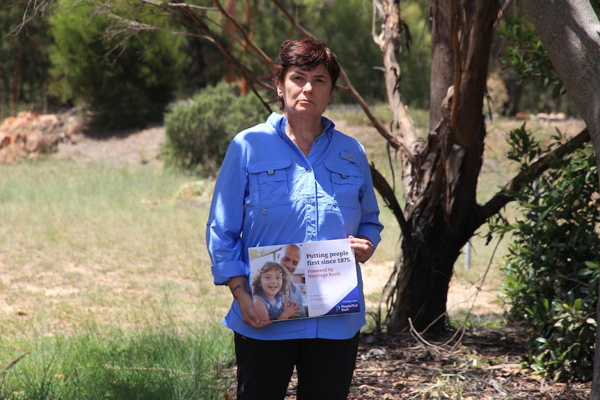 A woman holds a sign about bank closures.