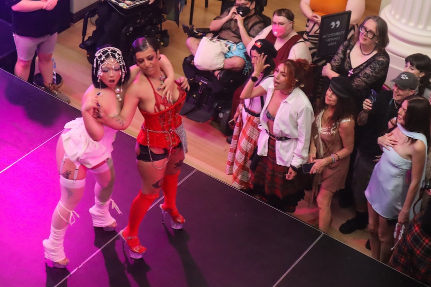 Two people on a stage, one wearing a white costume and the other wearing red.