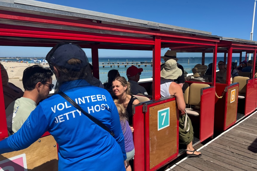 A  volunteer helps people get seated on the Busselton Jetty train